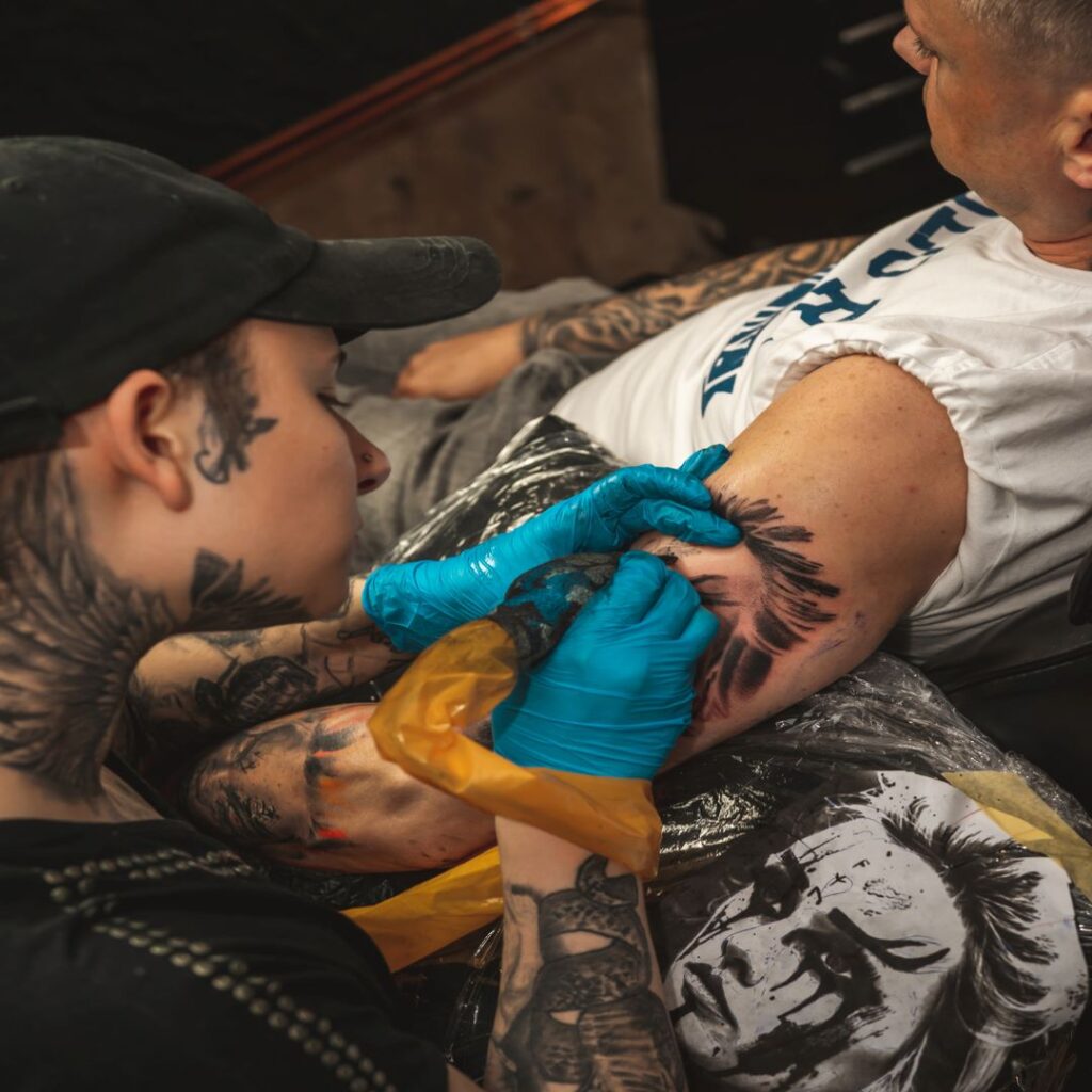 Mężczyzna robiący drugiemu tatuaż.